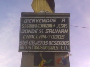 Spiritueller Materialismus - Schild an der Statue Corazon de Jesus Herz Jesu Beten für Auto Haus Dollars